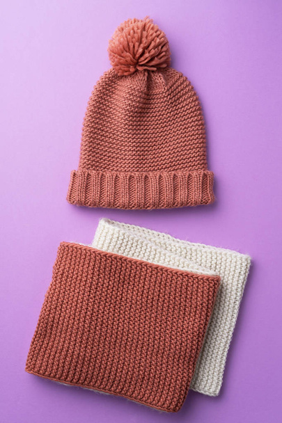 Knit winter hat and scarf over purple background - Zdjęcie, obraz