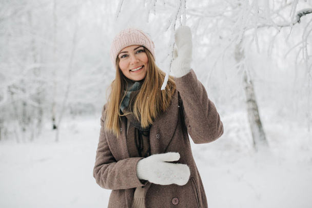 Image of happy blonde woman on walk in winter forest - Фото, изображение