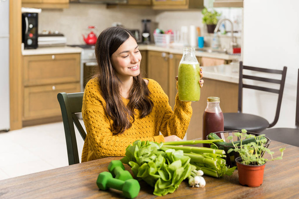 Ajuste mujer latina mirando batido de verduras mientras sigue la dieta verde
 - Foto, imagen