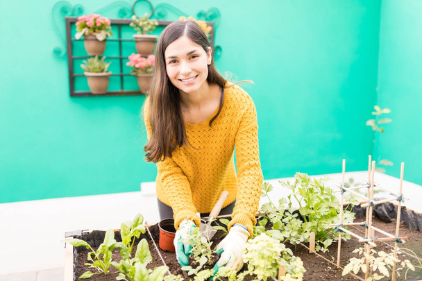 Счастливая латинская женщина сохраняет окружающую среду, выращивая растения в городском саду
  - Фото, изображение