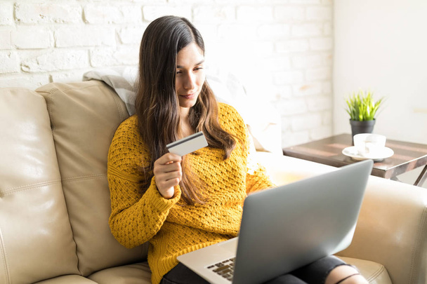 Mulher bonita fazendo compras on-line com cartão de crédito no laptop em casa
 - Foto, Imagem