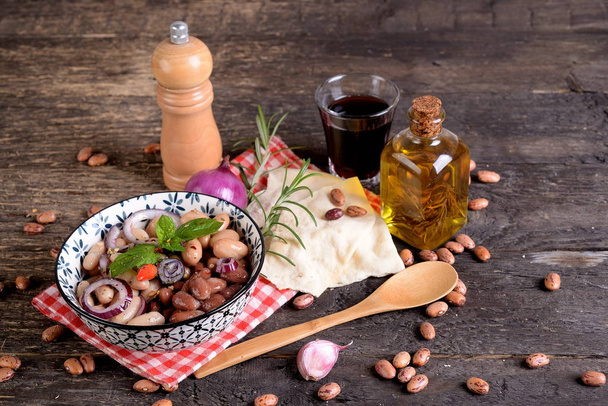Μπολ με Ρωμαϊκή φασόλια με κρεμμύδι, μυρωδικά και ελαιόλαδο στο τραπέζι - Φωτογραφία, εικόνα