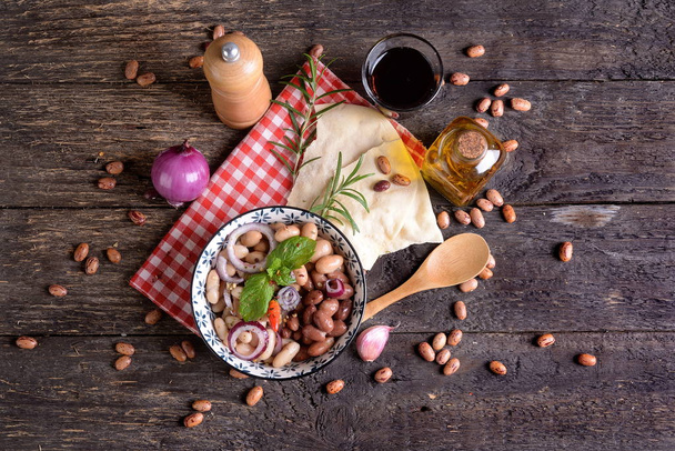 Bol aux haricots romains avec oignon, herbes et huile d'olive sur la table
 - Photo, image