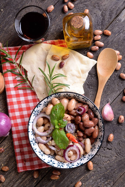 Bol aux haricots romains avec oignon, herbes et huile d'olive sur la table
 - Photo, image