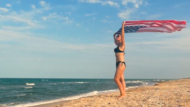 Deniz kenarında Amerikan bayrağı ile vatansever kadın stand. Ağır çekim - Video, Çekim