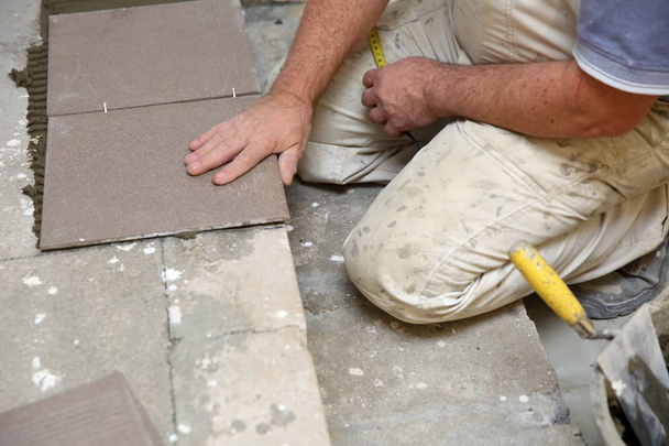 Будівельник влаштовує керамічну плитку на сходах всередині будівлі
. - Фото, зображення