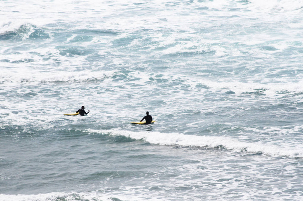 Силуэт двух серферов, плавающих в океане в Ньюкуэе, популярном месте для серферов. Ньюкей, Корнуолл, Великобритания
 - Фото, изображение