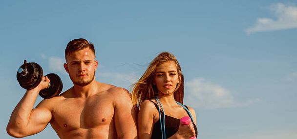 Fitness. Fitness training on blue sky. Fit man and woman with fitness tools outdoor. Fitness trainers with dumbbells. Commit to be fit, copy space - Foto, immagini