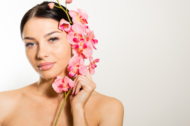 Beautiful girl holding pink flowers with perfect skin, lips. - Fotoğraf, Görsel