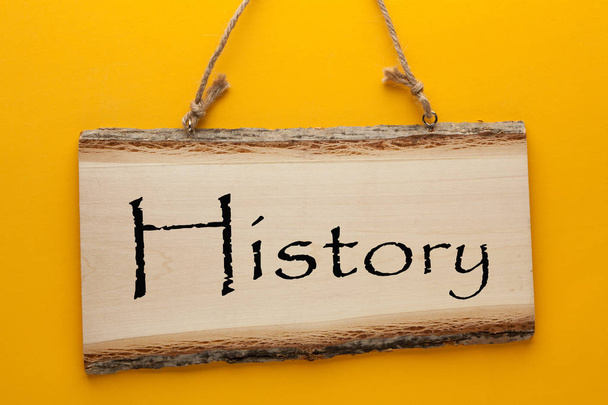 History word on wooden sign hanging on a rope on yellow background. Business concept - Photo, Image