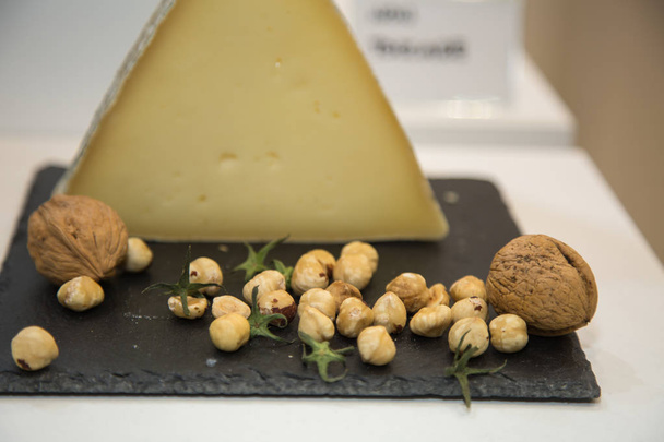 Triangular-shaped Cheese on Black Tablecloth with Raw Chickpeas and Big Walnuts. - Photo, Image
