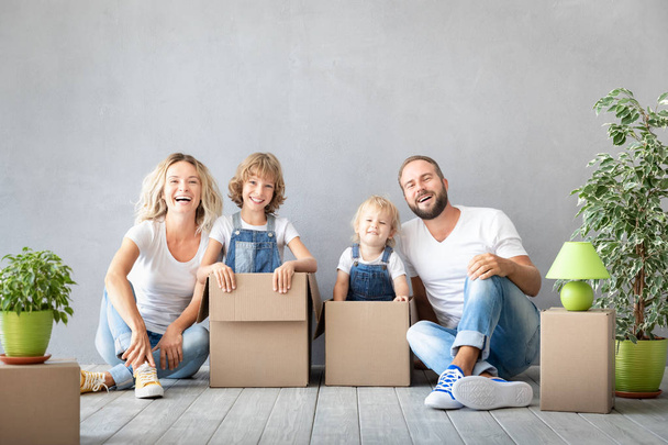 Happy family with two kids playing in new home. Father, mother and children having fun together. Moving house day and real estate concept - Photo, Image