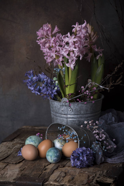 Happy Easter card template with colorful hyacinth flowers in bucket and colorful eggs on wooden table - Foto, afbeelding