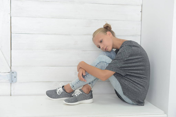 girl in a gray jacket and blue jeans in the Studio on a gray background - Foto, afbeelding