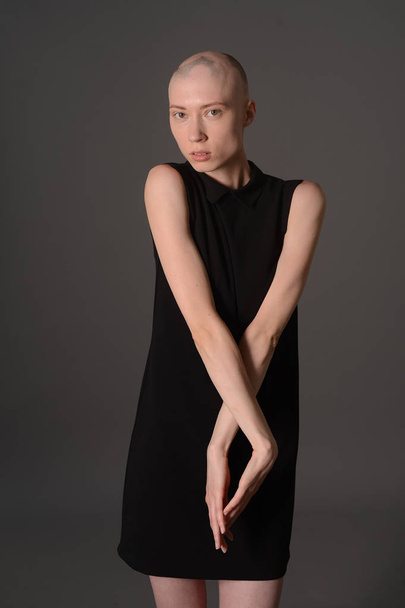 bald girl posing in Studio in black dress - Foto, afbeelding