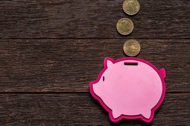 Pink piggy bank with coins on wooden background - Photo, Image