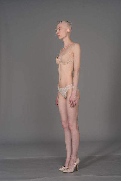 bald girl in beige lingerie posing on grey background - Foto, Bild