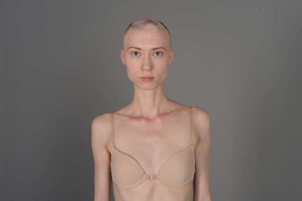 bald girl in beige lingerie posing on grey background - Foto, immagini