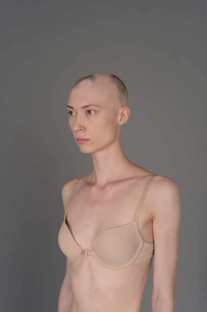 bald girl in beige lingerie posing on grey background - Fotoğraf, Görsel