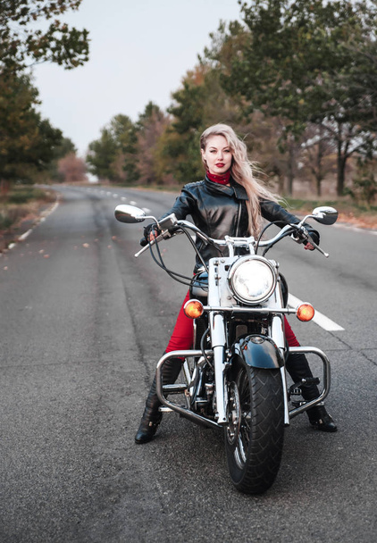 Gyönyörű kerékpáros nő pózol szabadtéri motorkerékpár az úton.  - Fotó, kép