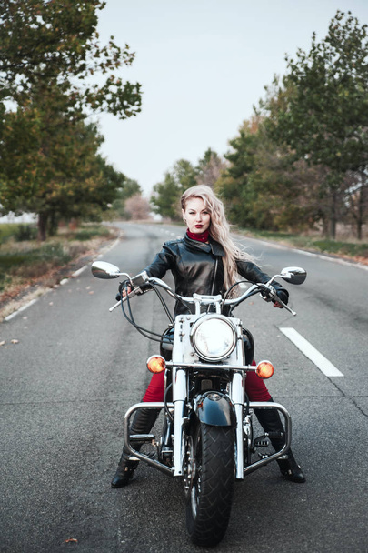 Hermosa mujer motorista posando al aire libre con la motocicleta en el camino
.  - Foto, imagen