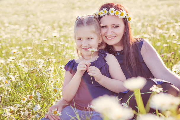 Mother with cute little child girl in the chamomile field in spring - Foto, Bild