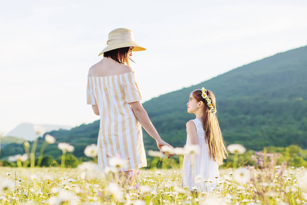 Mother and daughter in  field of daisies. Beautiful family in nature. - Foto, imagen
