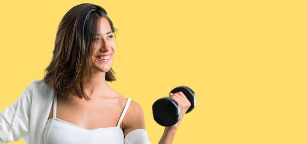 Sport woman making weightlifting on yellow background - Foto, Imagen