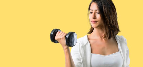 Sportlerin macht Gewichtheben auf gelbem Hintergrund - Foto, Bild