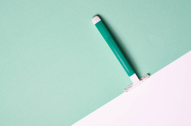Rasiermesser auf grün-weißem Hintergrund, minimalistisches Stilkonzept, Draufsicht, flache Verlegung - Foto, Bild