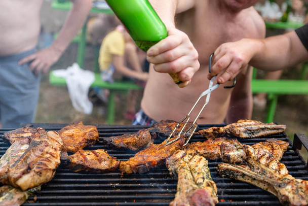 Друзья, жарящие мясные ребрышки и стейки, барбекю на открытом воздухе, пикник, отдых по выходным
 - Фото, изображение