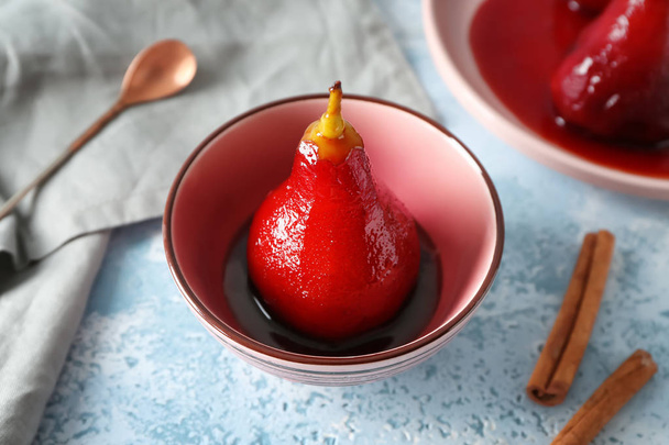 Bowl with delicious poached pear in red wine on color table - Photo, image