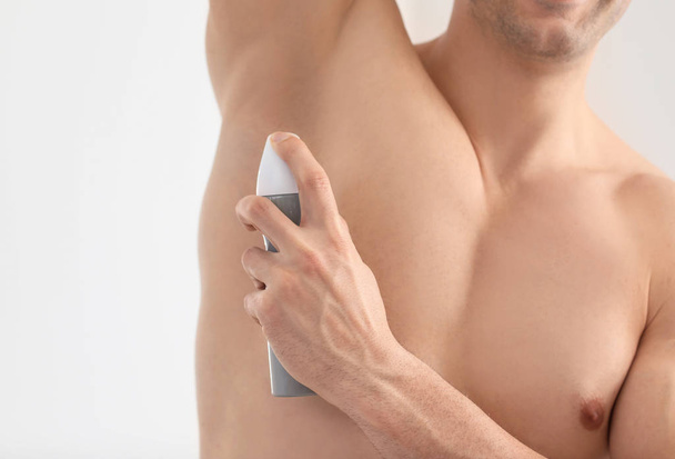 Handsome young man with deodorant in bathroom, closeup - Foto, Imagem
