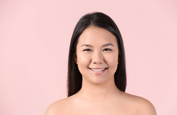 Portrait of young Asian woman with clear skin on color background - Foto, immagini