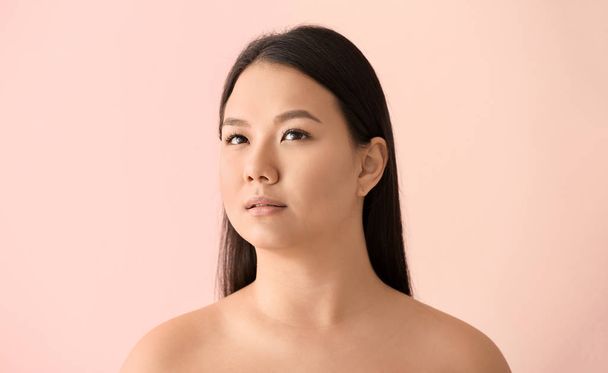 Portrait of young Asian woman with clear skin on color background - Foto, Imagem