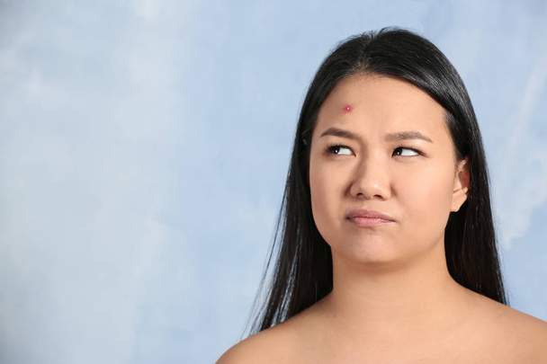 Portrait of young Asian woman with acne problem on color background - Foto, afbeelding