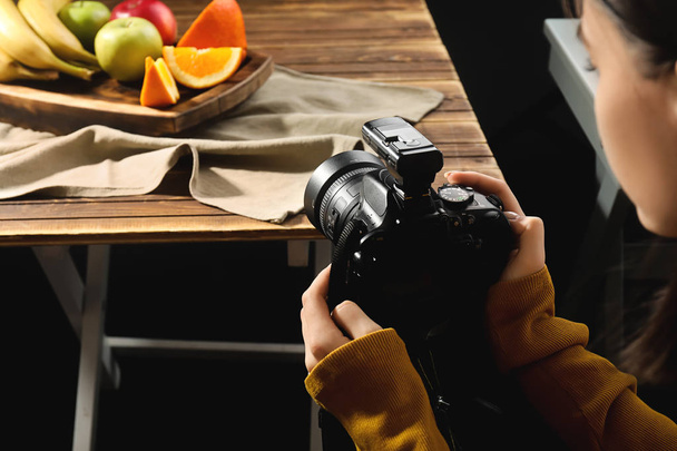 Mujer joven tomando fotos de frutas sabrosas en estudio fotográfico profesional
 - Foto, Imagen