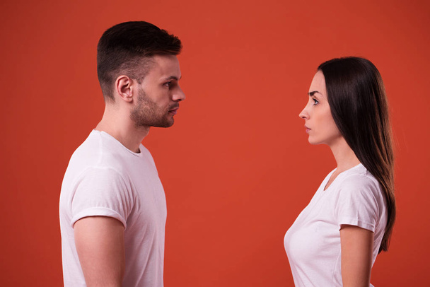 Side view photo of young serious couple standing face to face in studio - Fotó, kép