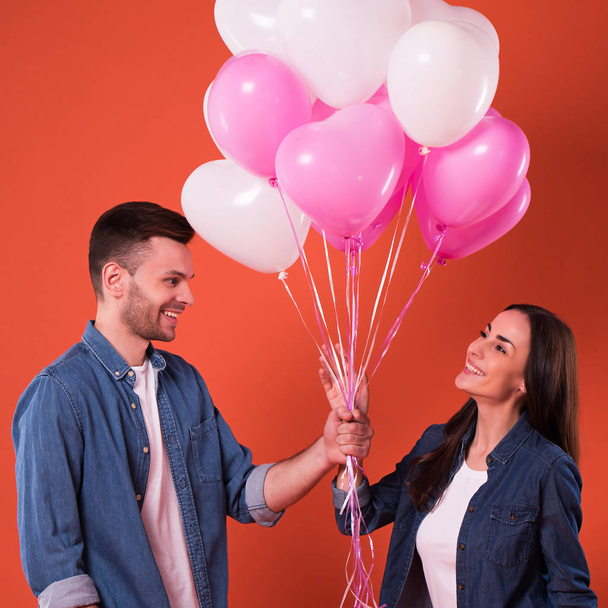 Young beautiful Couple in love are posing together with colorful balloons in casual wear. St Valentines day holiday - Foto, immagini