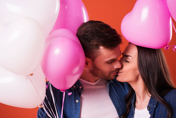 Young beautiful Couple in love are posing together with colorful balloons in casual wear. St Valentines day holiday - Фото, зображення