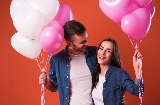Mladý nádherný pár v lásce, které jsou homologní spolu barevné balónky v neformální oblečení. St Valentines den dovolené - Fotografie, Obrázek
