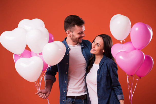 Young beautiful Couple in love are posing together with colorful balloons in casual wear. St Valentines day holiday - Foto, Imagem