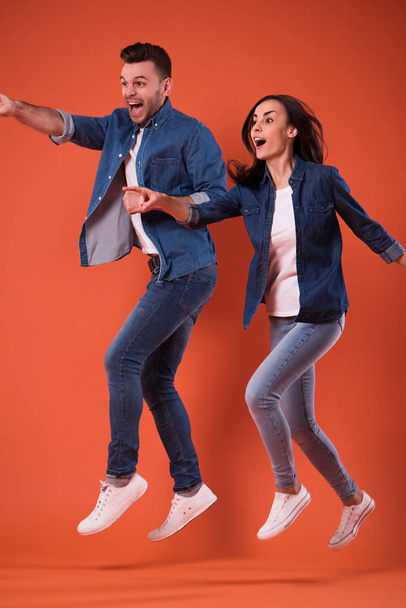 Full length portrait of a cheerful and excited young couple jumping together and celebrating success while running isolated in studio - Photo, image