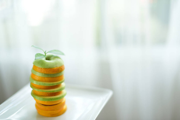 gestapelde schijfjes sinaasappel en appel met bladeren - Foto, afbeelding