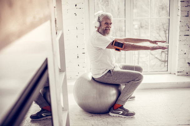 Pleased mature man sitting on fitness ball in gym - Fotoğraf, Görsel