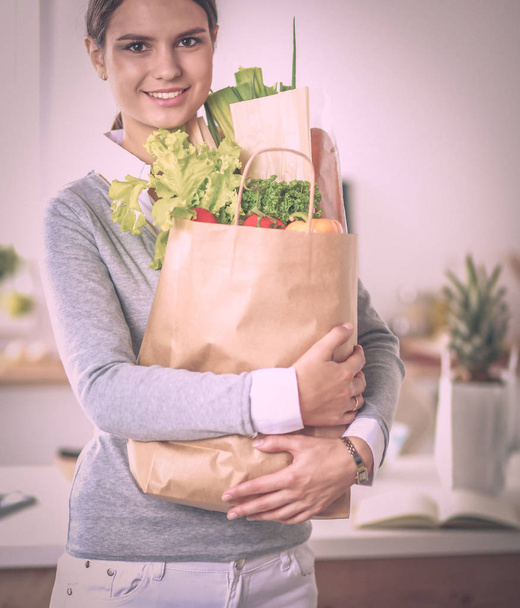 Young woman holding grocery shopping bag with vegetables Standing in the kitchen.  - Foto, Bild