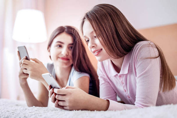 Glad two girls messaging with their phones - Фото, зображення