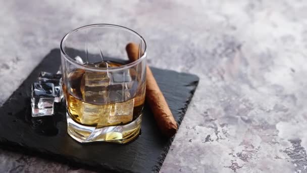 Glazen voor whisky met ijsblokjes en sigaar - Video