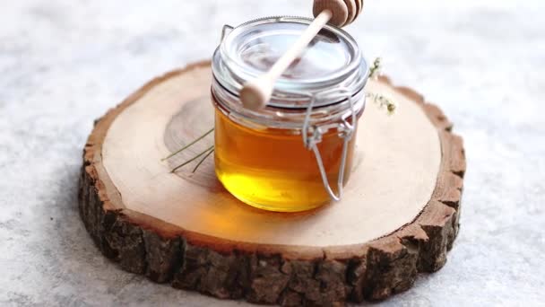 Tarro de vidrio lleno de miel fresca colocado en rebanada de madera
 - Imágenes, Vídeo