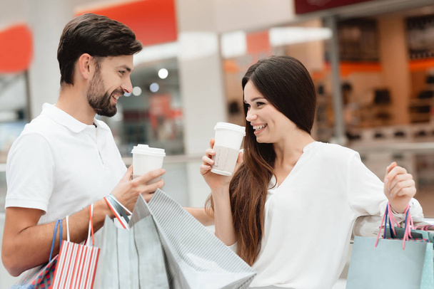 Man and woman in shopping mall. Couple is drinking coffee, laughing. - Photo, image